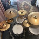 Sada bubnů a činelů značky Zildjian a TAMA. Na bubnech jsou viditelné nápisy TAMA a EVANS, na činelech značka Zildjian a u některých nápis CUSTOM. Ce…