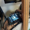 Na těle banjona je připevněn černý elektronický preamp s ovládacími prvky a nápisy VOLUME, TONE a BASS. Na zařízení je viditelné červené logo „Sturbr…