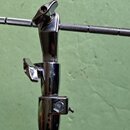Detail chromovaného stojanu s teleskopickou horní částí. Stojan má tři utahovací knoflíky v různých pozicích a horní horizontální tyč je opatřena čer…