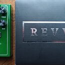 Zelený kytarový efekt s ovládacími knoflíky popsanými jako BASS, MIDDLE, TREBLE, VOLUME a GAIN. Na pedálu je přepínač DRIVE s označením BLUE a RED, n…