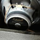 Zadní strana reproduktoru s kovovým šasi a černým magnetem. Na magnetu je zlatý nápis Marshall AMPLIFICATION Heritage a menší text Part No. 9311. K t…