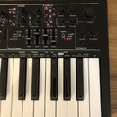 Černý syntetizátor s klaviaturaí. Na horním panelu jsou viditelné nápisy sekcí Mixer, Filters, Envelopes a Effects s doprovodnými ovládacími prvky. P…