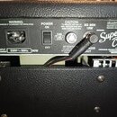 Zadní panel kytarového komba v černé barvě. Je na něm vidět nápis Super Champ, logo FENDER MUSICAL INSTRUMENTS CO CORONA CA U.S.A. MADE IN MEXICO a t…