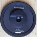 Černý plastový elektronický činel značky Roland. Na povrchu je bílý nápis „Roland“ s logem a modelové označení „CY-14R-T“. Dole je uveden text „Rolan…