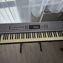 Šedý digitální klavír s nápisem KORG N264. Instrument má standardní klávesnici a ovládací panel s displejem a několika tlačítky. Povrch je v dobrém s…