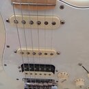 Bílá elektrická kytara s bílým pickguardem a javorovým hmatníkem. Nástroj má tři snímače s krémovými kryty, přičemž spodní je humbucker. Na ovládacíc…