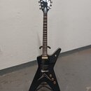 Černá elektrická kytara s tělem ve tvaru hvězdy a chromovanou hlavou. Na hlavě je viditelné logo DEAN. Kytara má dva humbuckery, tři ovládací knoflík…