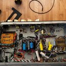 Fotografie zachycuje vnitřek elektronického zařízení s otevřeným šasi. Uvnitř jsou vidět dva transformátory, kondenzátory, vakuumové elektrony a rozv…