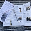 Fotografie zachycuje několik listů papíru s textem v češtině a angličtině, pravděpodobně se jedná o uživatelskou příručku. V levém dolním rohu je vid…