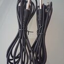 Dvě černé kábely s konektory typu jack na obou koncích. Káble jsou svázány černými stahovacími pásky. Na kablech nejsou viditelné žádné značky ani ná…