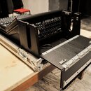 Černý syntezátor s klaviatura v přepravním kufru z hliníku a černého materiálu. Na předním panelu je viditelný nápis M3XR a logo KORG. Kufr má kovové…