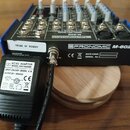 Černý mixážní pult s modrými bočními panely a bílým nápisem PRONOMIC M-602. Na přístroji je nalepená bílá nálepka s textem TRIBE OF MISERY a viditeln…