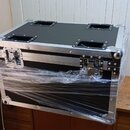 Černý transportní kufr s hliníkovými hranami a kovovými rohy. Na horní straně jsou čtyři zapadlé rukojeti. Kufr je zčásti omotaný průhlednou plastovo…