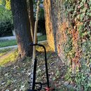 Na fotografii je kytara s krémovým nebo bílým povrchem, umístěná na černém stojanu. Nástroj je zobrazen z profilu a zadní strany, značky nebo modely…