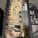 Fotografie zachycuje vnitřek elektronického zařízení s otevřeným šasi. Je viditelná základní deska s osazenými součástkami, kondenzátory a zapojením…