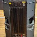 Zadní strana šedého reproduktoru v plastovém pouzdře. V horní části je ovládací panel s nápisy INPUT, OUTPUT, LIMITER, PHASE a LAST OUTPUT, doprováze…