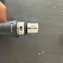 Detailní pohled na horní část mikrofonu s černým tělem a stříbrnou mřížkou. Na těle je viditelný bílý nápis SHURE. Povrch mřížky vykazuje drobné neči…