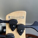 Záběr na zadní stranu hlavy kytary z přírodního dřeva. Je zde vyrazený nápis F0208502 a pod ním text MADE IN JAPAN CE. Na hlavě jsou černé ladicí mec…