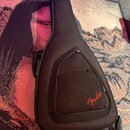 Černý polstrovatý pouzdro na kytaru z textilního materiálu. Na přední straně je umístěna kapsa s červeným nápisem Fender. Pouzdro vykazuje mírné zneč…