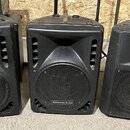 Tři černé plastové reproduktory s integrovanými úchopy z hnědé kůže. Krajní dva mají v dolní části logo RH SOUND, prostřední reproduktor má nápis AME…