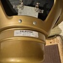 Zlatý reproduktor s kovovým rámem. Na zadní straně je bílá nálepka s nápisy CELESTION, T5671B G10-GOLD ΩΩ a MADE IN UK. V horní části jsou vidět dva…