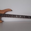 Světle hnědá elektrická basová kytara s přírodním dřevem. Na hlavě je viditelné logo Washburn. Hриф má tmavý hmatník s kulatými polohovými značkami a…