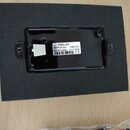 Černý obdélníkový komponent položený na šedém plátnovém podkladu. Na povrchu je bílá nálepka s nápisy EMG-57, MADE IN USA 4305.01, (21)4513695 04/17/…