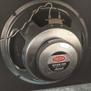 Fotografie zachicuje zadní stranu reproduktoru v černé skříni. Na středovém magnetu je štítek s nápisy CELESTION, G12E-60 a Marshall AMPLIFICATION LT…
