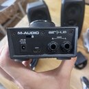 Zadní strana černého zařízení s nápisy M-AUDIO a air HUB. Jsou zde vidět konektory DC IN 5V⎓3A, USB a dva výstupy MAIN označené R a L. Povrch zařízen…