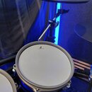Elektronický bicí komplet s modrým korpusem padů. Na bílém povrchu padu je černé logo s písmenem F a nápisem Designed in Japan. Součástí sestavy jsou…