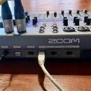 Zadávací panel stříbrného mixážního pultu značky ZOOM. Jsou zde viditelné nápisy POWER, DC IN, HOST, MODE, DEVICE CLASS COMPLIANT MODE a SAMPLE RATE,…