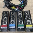 Čtyři černé konektory s kombinovanými XLR/jack vstupy, rozdělené do skupin po čtyřech. Každý blok má barevný proužek (červený, modrý, zelený, žlutý)…