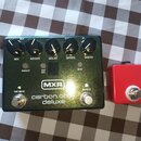 Zelený kytarový efekt s nápisy MIX, REGEN, DELAY, SPEED a WIDTH u ovládacích knoflíků. Na spodní části je logo MXR a text carbon copy deluxe, dále ná…