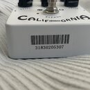 Bílý kytarový efekt s nápisem CALIF SOUND ORNIA. Na boku je nalepená čárová etiketa s číslem 31830205307. Na horní straně jsou viditelné nápisy LEVEL…