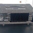 Zadní strana kytarového komba v černém textilním potahu s kovovým chladičem. Na levé straně je nápis MELODYNE POWER, CONSUMPTION 210 W / 50 Hz - 60 H…
