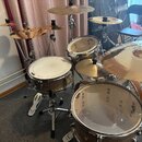 Celá bicí souprava s několika cikly a bubny v hnědém provedení. Na bubnech jsou viditelné loga YAMAHA. Cimbály mají nápisy CUSTOM a Zildjian. Součást…
