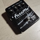 Černý kytarový efekt s nápisem FuzzMo a podtitulem Fuzz Mode Ultra High Gain Distortion. Na šasi je viditelné logo EBS a čtyři ovládací knoflíky s po…