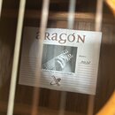 Fotografie zachycuje vnitřní štít kytary s nápisem aragón. Štít obsahuje černobílou fotografii ruky na hředni kytary a text Guitarras finas fabricada…