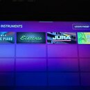Fotografie zachicuje displej zařízení s menu INSTRUMENTS. Jsou zde vidět čtyři dlaždice s nápisy FABRIC ELECTRIC PIANO, Electric, JURA a RING THE ALA…
