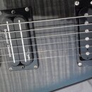 Detail těla elektrické kytary s tmavým povrchem z plámenového javoru. Nástroj má dva humbuckery v černých rámečcích; na kobylnívém snímači je nápis S…