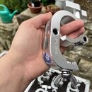 Stříbrná kovová svorka v podobě C-clamp s utahovacím šroubem a křídlovou maticí. Na boku je vyryt nápis SWL-250KGS a nalepená modrá kulatá nálepka s…