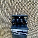 Černý kytarový efekt s nápisem Fender '65 Deluxe Reverb Amp a označením FDR-1. Na horní straně jsou čtyři černé otočné ovířky s popisky LEVEL, GAIN,…