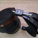 Over-ear sluchátka s dřevěnými mušlemi a černým polstrováním. Na vnější straně mušle je nápis PLANAR MAGNETIC TECHNOLOGY a na spojovacím prvku logo A…