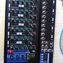 Černý mixážní pult s modrým rámem. Na pravé straně jsou vstupy pro mikrofony (XLR) a linkové vstupy, v dolní části je malý displej. Ovládací panel ob…