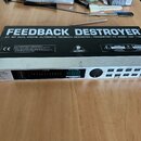 Stříbrný rackový procesor s nápisem FEEDBACK DESTROYER a označením MODEL DSP 1100. Na horní straně je logo BEHRINGER a varovné štítky s nápisy CAUTIO…