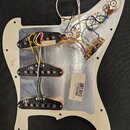 Bílá pickguard s hliníkovým stíněním, na které jsou namontovány tři snímače s černými plastovými kryty. Snímače jsou označeny čísly 131, 132 a 133. V…