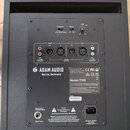 Zadní strana černého studiového subwooferu značky ADAM AUDIO Berlin, Germany. Zařízení má modelové označení Model: T10S a sériové číslo 4100819364. N…