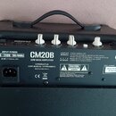 Zadní strana černého basového komba s nápisem CM20B 20W BASS AMPLIFIER a logem Cort. Na štítku je uveden vstupní napětí 220-240V~50/60Hz a Serial Num…