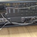 Zadní strana černého kytarového zesilovače s kovovou mřížkou. Jsou zde viditelné nápisy FX LOOP (SEND, RETURN), FOOTSW, INFINIUM (REPLACE VALVE WHEN…