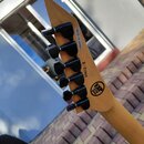 Hlava kytary z přírodního dřeva s šesti černými ladičkami. Na zadní straně hlavy je bílá nálepka s nápisem MADE IN JAPAN, černý nápis K-23086 a kulat…